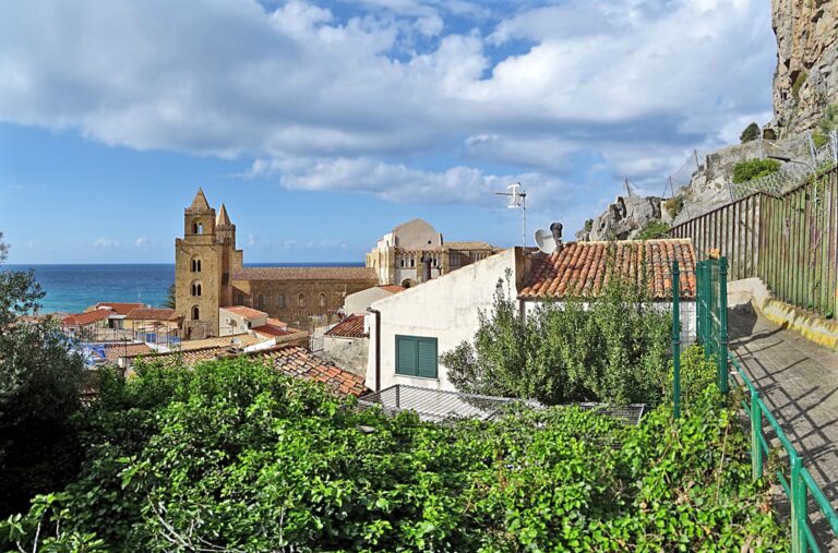 Torri e fianco del Duomo di Cefalù fra tetti, mare e pendici della Rocca