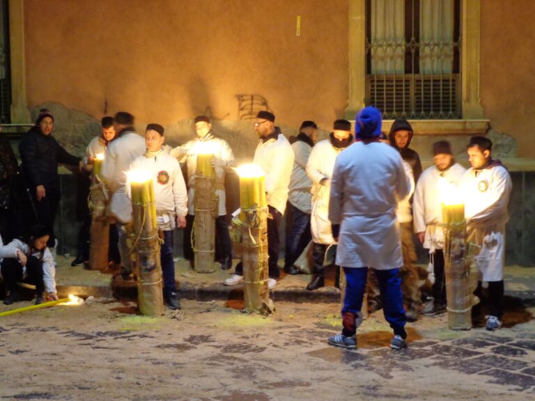 Devoti in abito bianco accanto a grandi cerei accesi durante la festa di Sant’Agata a Catania