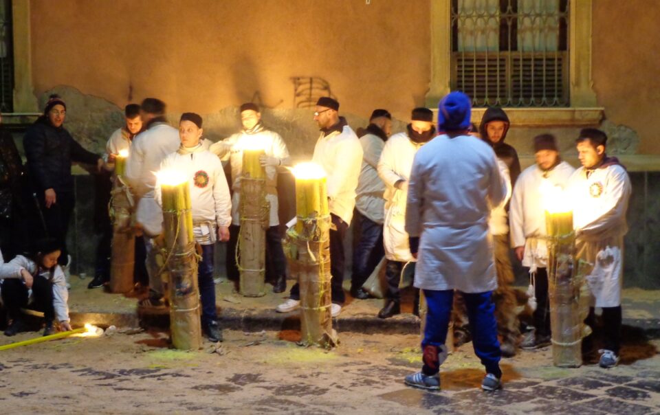 Devoti in abito bianco accanto a grandi cerei accesi durante la festa di Sant’Agata a Catania