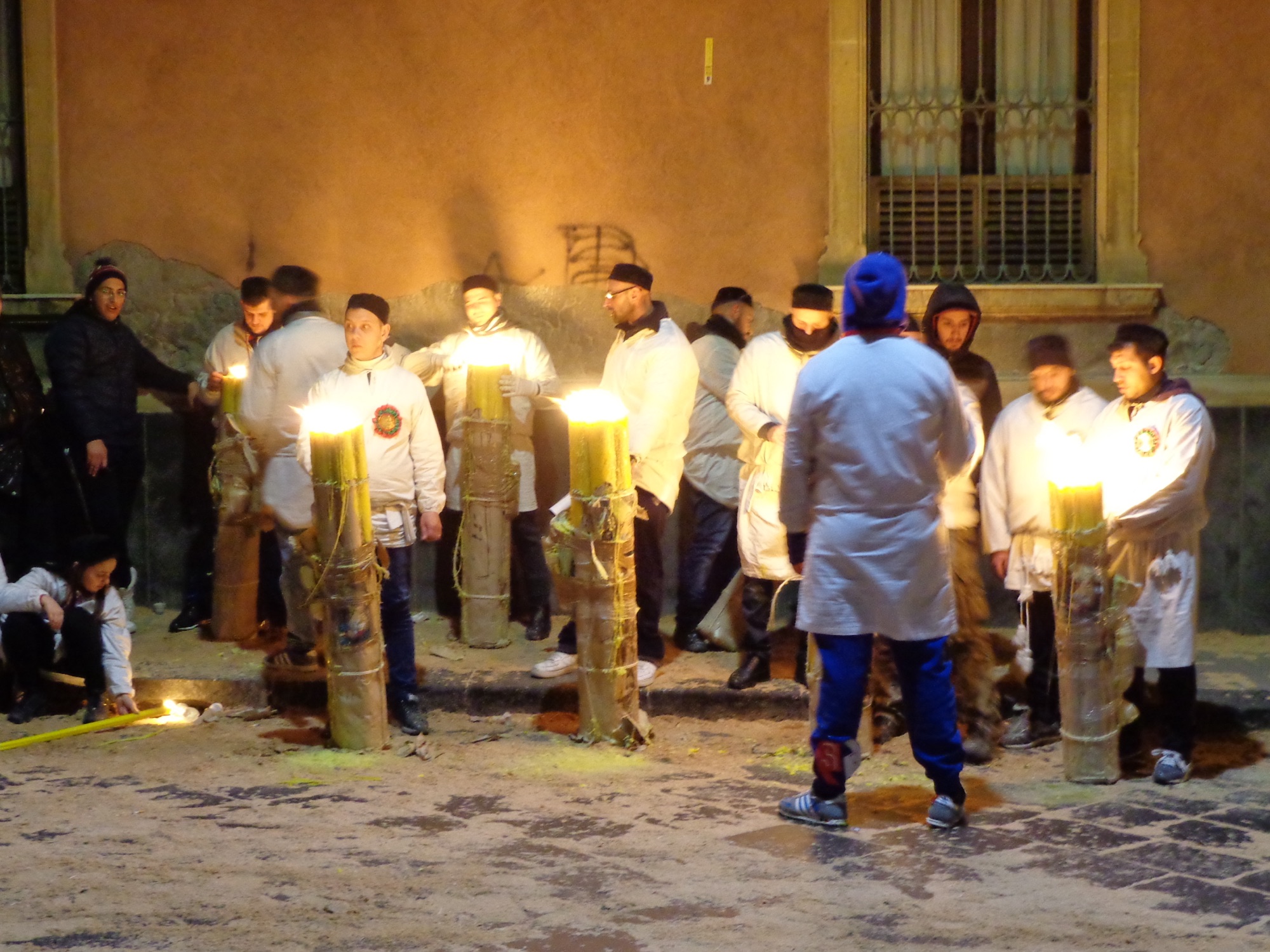 Devoti in abito bianco accanto a grandi cerei accesi durante la festa di Sant’Agata a Catania