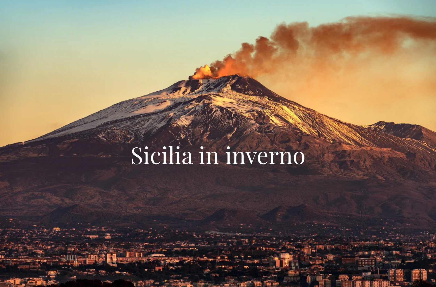 Etna con una colonna di fumo e città in basso, con il titolo Sicilia in inverno.